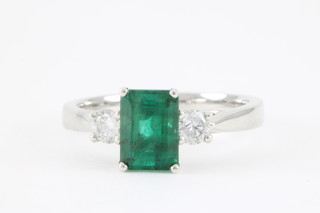 An 18ct white gold emerald and diamond ring, the centre rectangular cut emerald approx 1.63ct flanked by brilliant cut diamonds approx. 0.27ct