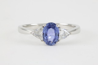An 18ct white gold sapphire and diamond dress ring, the oval cut sapphire approx. 0.87ct flanked by triangular cut diamonds approx 0.3ct