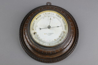 J H Steward. An Edwardian aneroid barometer contained in a circular carved oak case 8 1/2"