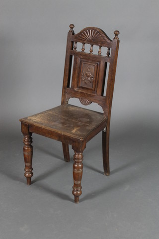 A Victorian oak hall chair with bobbin turned decoration, the back with armorial carving and having a solid seat, on turned supports