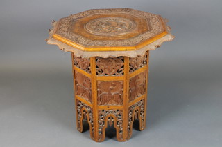 An octagonal carved and pierced Indian hardwood table, the top carved a figure of an elephant, the base fitted a cupboard enclosed by a panelled door 24"h x 26 1/2"
