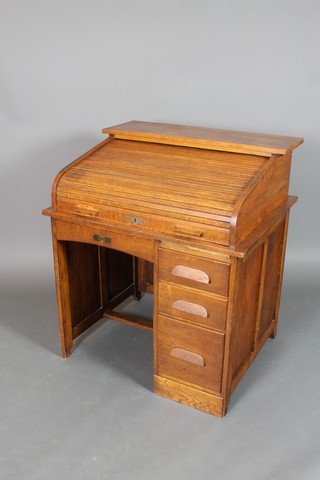 An Edwardian oak roll top desk, the tambour shutter revealing a fitted interior and pigeon holes flanked by 3 long drawers 42"h x 36"w x 30 1/2"d