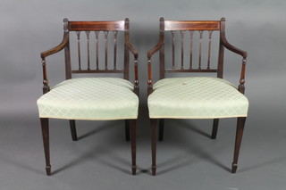 A pair of 19th Century mahogany stick and rail back carver chairs with upholstered seats on square tapering supports ending in spade feet 