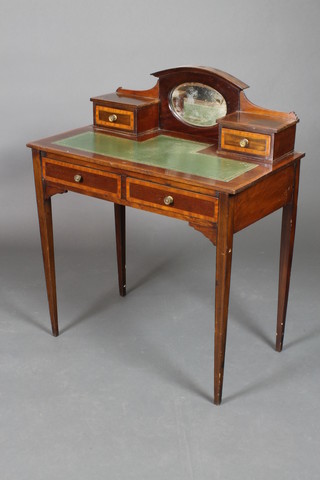 An Edwardian mahogany writing table inlaid crossbanding, the arch shaped back fitted an oval plate mirror flanked by a pair of drawers, the base with green inset writing surface above 2 long drawers, raised on square tapering supports 36 1/2"h x 30"w x 17"d