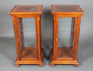 A pair of square mahogany pedestal cabinets, the interiors fitted adjustable shelves enclosed by glazed panelled doors, raised on bun feet 37"h x 18"w x 18 1/2"d