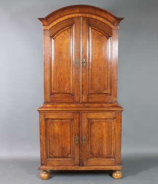 A 17th Century style Continental oak arch shaped cabinet on cabinet, the upper section fitted a niche and drawers enclosed by a pair of panelled doors, the base fitted a cupboard enclosed by a panelled door, raised on bun feet 83"h x 40 1/2"w x 20 1/2"d 