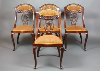 A set of 4 late Victorian carved and pierced mahogany salon chairs with vase shaped slat backs, the seats of serpentine outline, raised on cabriole supports