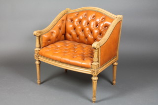 A Georgian style bleached mahogany show frame armchair upholstered in buttoned back brown hide, raised on turned and fluted supports 