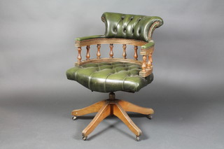 A mahogany tub back revolving office chair upholstered in green buttoned leather
