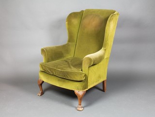 A Georgian style winged armchair upholstered in green Dralon, raised on carved cabriole supports