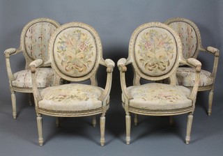 A set of 4 French carved open arm salon chairs, the seats and backs upholstered in wool work, raised on turned and fluted supports 