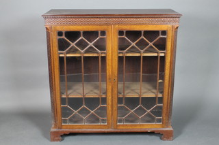 An Edwardian Chippendale style mahogany bookcase with moulded and dentil cornice, blind fret work frieze and canted corners, the interior fitted adjustable shelves enclosed by astragal glazed panelled doors, raised on bracket feet 42"h x 41"w x 15"d 