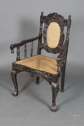 An Anglo Indian carved hardwood open arm chair with woven cane seat and back, carved Welcome, raised on cabriole supports