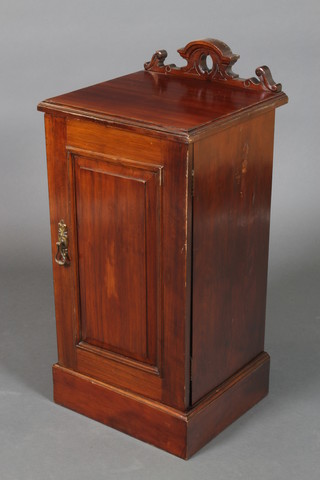 An Edwardian walnut pot cupboard with carved raised back, enclosed by a panelled door and raised on a platform base 33"h x 15 1/2"w x 14 1/2d 
