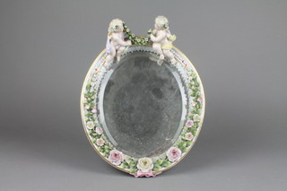 A 19th Century German oval porcelain easel mirror surmounted by cherubs, the frame with a band of roses 12"