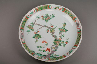 An 18th Century famille verte shallow dish, the border with motifs enclosing exotic birds amongst flowering trees, flower mark to base 16" (There are several cracks, the rim is fritted and chipped)