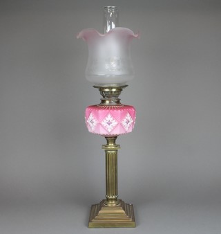 An opaque pink glass oil lamp reservoir with clear glass shade, raised on a reeded and stepped brass base 27" 