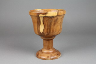 A turned yew pedestal vase, raised on a spreading foot 9"