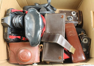 A Wrayflex camera, a Werra Camera 1, a Canon T70 camera and lens marked Hoya HMC wide-auto F=28mm 1:2.8 lens, a Yashica A camera, a Braun Puxette camera, a canon T70 camera, an Ricoh Matic camera, a Polaroid One Step 600 camera, a pair of Tasco 16/50mm binoculars, a pair of Sunagor 12-40 zoom binoculars and 3 light meters 