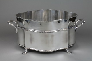 A silver plated serpentine champagne cooler with twin handles on pad feet