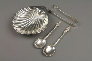 A silver shell butter dish on ball feet, a pair of apostle style tea spoons and a pair of nips, approx 126 grams