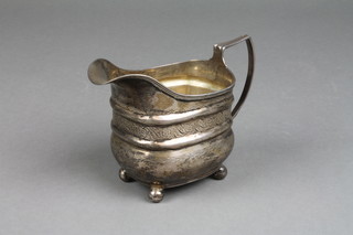 A George III silver cream jug with reeded decoration and a chased floral band on ball feet, London 1810, approx. 96 grams