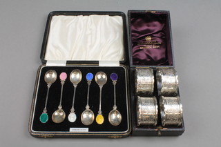A cased set of 4 Victorian silver napkin rings with chased decoration Birmingham 1895, approx. 80 grams and a cased set of guilloche enamelled teaspoons (f)