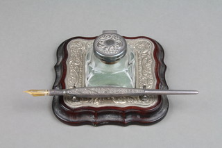 A repousse silver mounted ink stand with mounted ink well, pen rest and pen