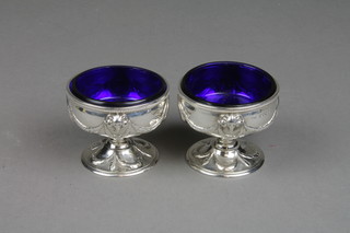 A pair of Victorian silver pedestal salts of Adam style with rams heads, swags, festoons and vacant cartouches, London 1863, blue glass liners