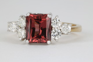 A 9ct gold gem set dress ring, the centre emerald cut stone flanked by 3 brilliant cut diamonds