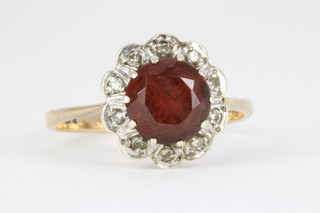 A 9ct garnet and diamond cluster ring, the centre stone surrounded by 10 diamond chips 