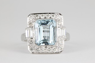 An 18ct white gold aquamarine and diamond cluster ring, the rectangular centre stone approx. 5.1ct, surrounded by 16 brilliant cut diamonds and flanked by 2 baguette cut diamonds, approx 1.05ct