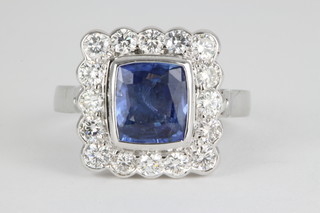 A 14ct white gold sapphire and diamond cluster ring, the rectangular cut sapphire approx 2.92ct surrounded by 16 brilliant cut diamonds approx. 1.05ct 