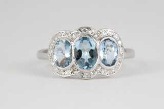 An 18ct white gold 3 stone aquamarine and diamond cluster ring, the aquamarine approx. 1.6ct surrounded by brilliant cut diamonds
