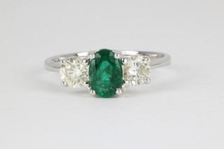 An 18ct white gold emerald and diamond ring, the centre oval cut emerald approx. 0.75ct flanked by single diamonds, each approx. 0.4ct 