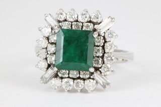 An 18ct white gold emerald and diamond cluster ring, the centre emerald approx 3cts surrounded by 28 brilliant cut diamonds interspersed with 4 baguette cut diamonds 
