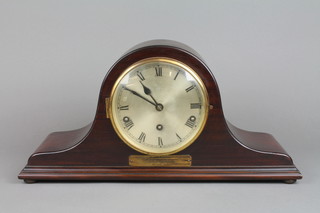 A chiming mantel clock with silvered dial and Roman numerals contained in a mahogany arch shaped case