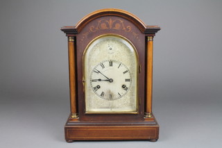 An Edwardian bracket clock with 5 1/2" arched silvered dial and Roman numerals, striking on a gong, contained in an inlaid mahogany case with columns to the sides 