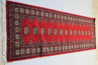 A Royal Mori red ground Bokhara style runner with 13 octagons to the centre 102" x 32"