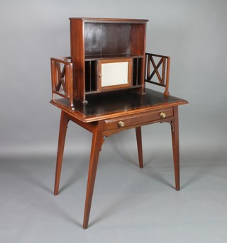 An Edwardian Liberty's style mahogany writing table with raised super structure to the back fitted pigeon holes and cupboard enclosed by a panelled door and with pierced three-quarter gallery, the base fitted a black writing surface above 1 long drawer, raised on splayed feet, 50"h x 33"w x 20"d