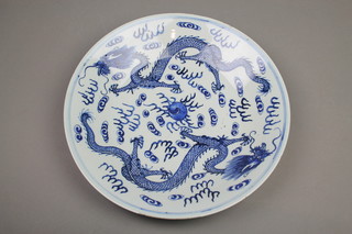 An 18th Century Chinese blue and white shallow bowl decorated with 2 dragons chasing a flaming pearl amongst clouds 15" (star crack)