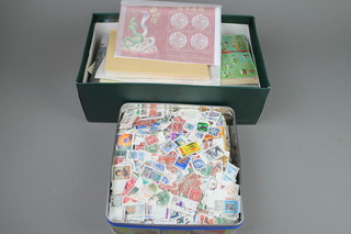 A metal biscuit tin and a shoe box containing a collection of various stamps