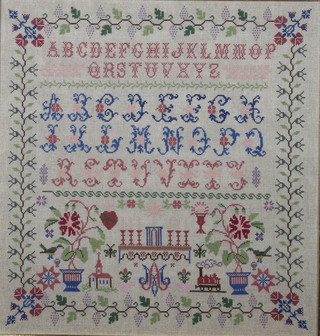A woolwork sampler with altar, church, steam engine and alphabet within a floral border 19" x 18" contained in a mahogany frame 