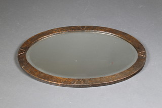 An Art Nouveau oval bevelled plate wall mirror contained in a planished copper frame 19" x 27" 