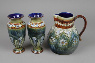 A Doulton Lambeth baluster jug with a brown band of stylised leaves, the mottled blue body with flowers 8598 7", a pair of ditto oviform vases with stylised flowers 7"