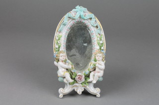 A 19th Century German oval porcelain easel mirror decorated with ribbons and flowers with 2 seated cherubs 7" 
