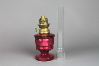 A Victorian cranberry faceted oil lamp with brass mounts and chimney 14"