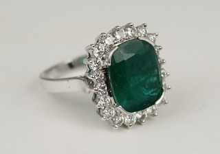 An 18ct white gold emerald and diamond ring, the cushion cut emerald surrounded by  20 brilliant cut diamonds, size P 1/2
