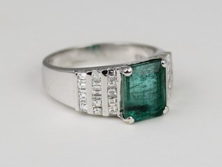 A 14ct white gold emerald and diamond cocktail ring, the emerald cut diamond approx. 4cts in a stepped diamond set mount, approx 1 ct, size P 1/2