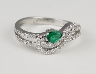 A 14ct white gold emerald and diamond whirl ring, size O